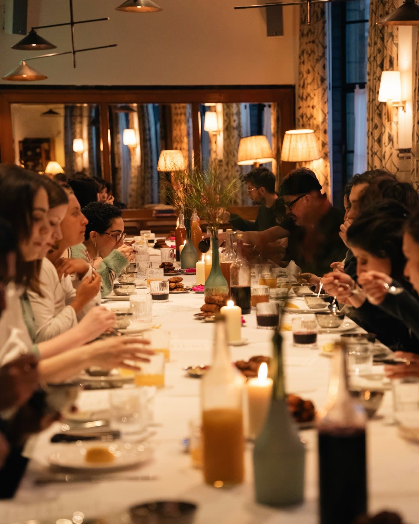 Guests sitting along a long candlelit dinner table